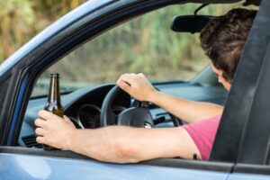Man drinking alcohol while driving a car
